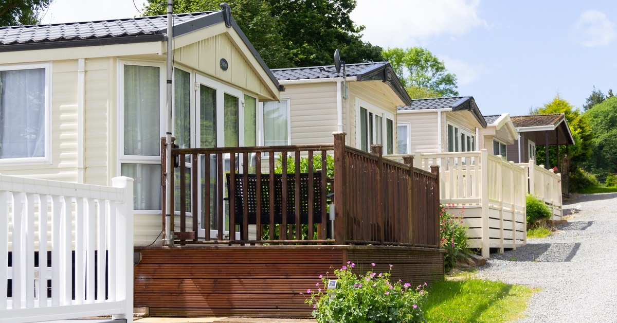 A row of mobile homes line up along a pebble drive. Each mobile home has a small porch on the front. A row of mobile homes line up along a pebble drive. Each mobile home has a small porch on the front.