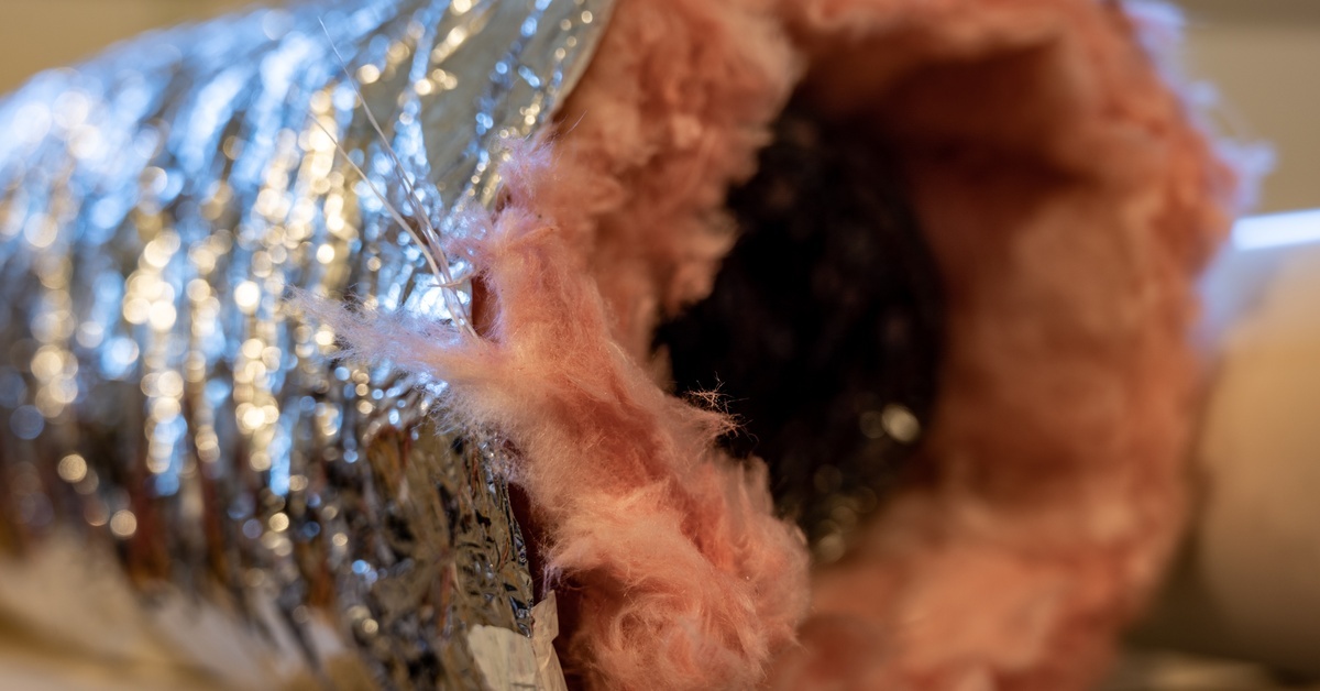 A flexible duct is covered in pink insulation and wrapped in a silver thermal layer for added energy efficiency.