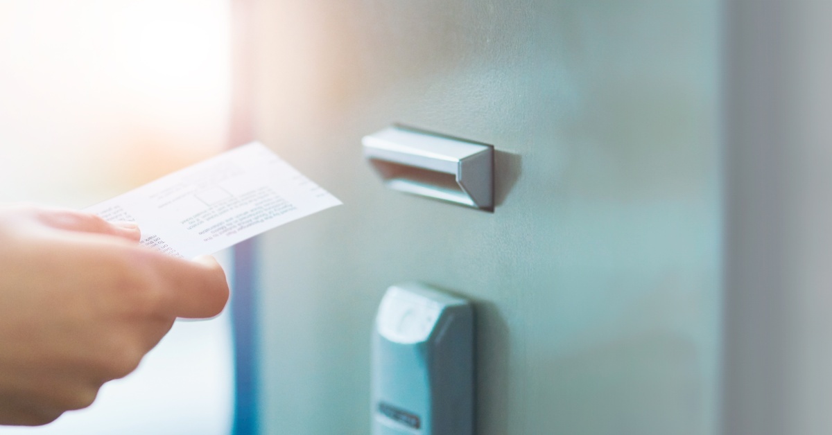 A person holding a plastic key card near a card reader to gain access through a secure building's doorway.