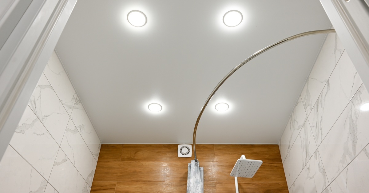 Transform Your Small Mobile Home Bathroom With These Tips The ceiling of a mobile home bathroom shower with four canned lights, a wood paneled wall, and tiling on the shower.